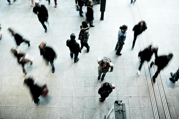 an aerial photo of a crowd of people walking across an open area