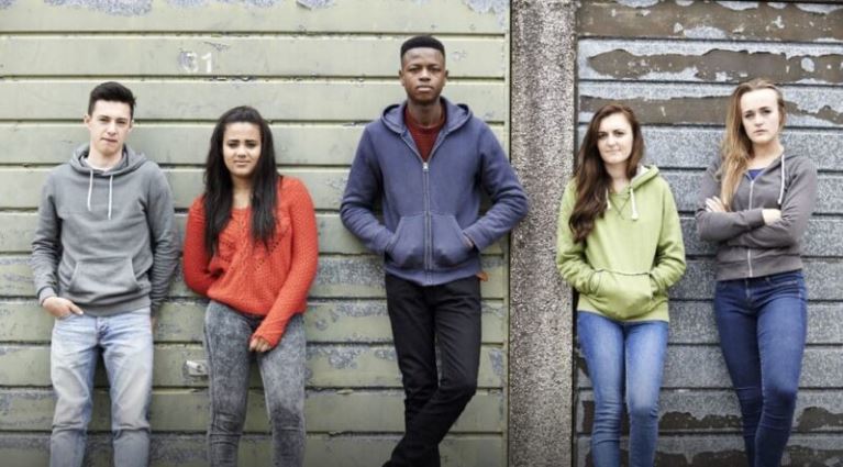 five young people leaning against a wall