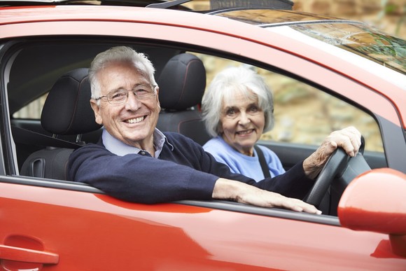 Elderly man and women looking happy in a car