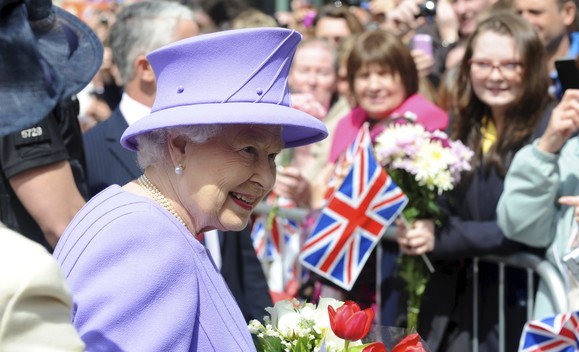 Her Majesty The Queen during her visit to Exeter. She is saying hello to crowds who are waving flags and cheering.