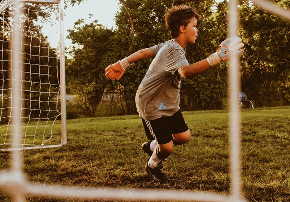 Boy playing football, in goals