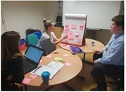 Our Public Health team sitting around a desk with post-its and a white board