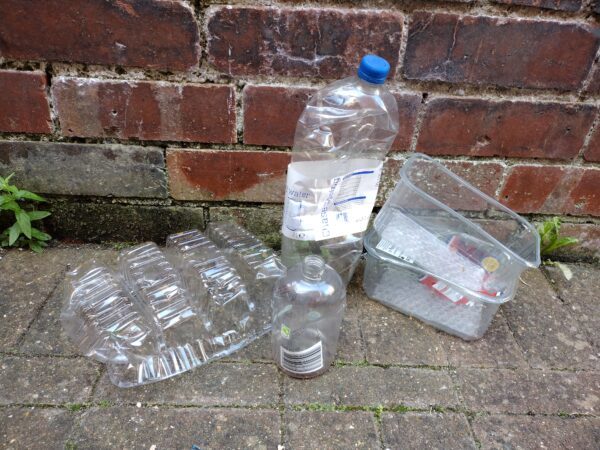 Plastic bottles on the ground, against a brick wall.