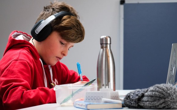 teenage boy working at laptop with headphones on