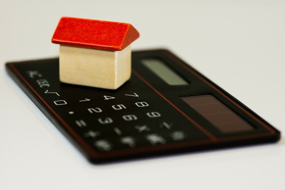 image shows a model of a miniature house sitting on top of a calculator