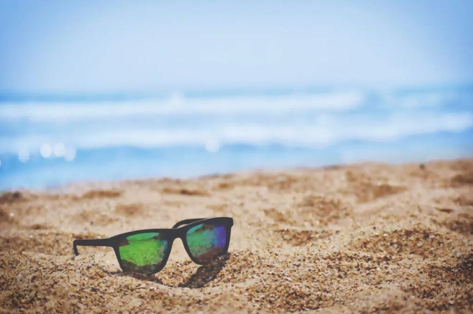 sunglasses laid on the sand, in the sun, on the beach