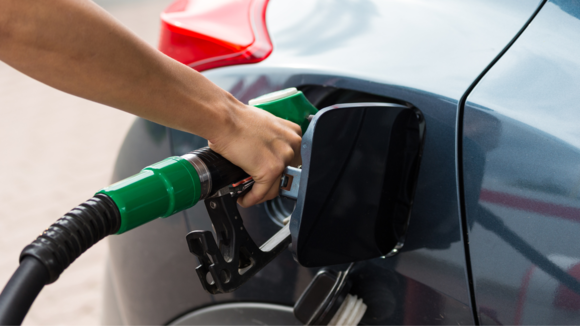 A hand holding a petrol pump while filling the car with fuel