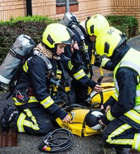 three firefighters doing a breathing apparatus exercise, including one woman