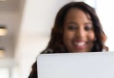 Black woman smiling behind a laptop screen