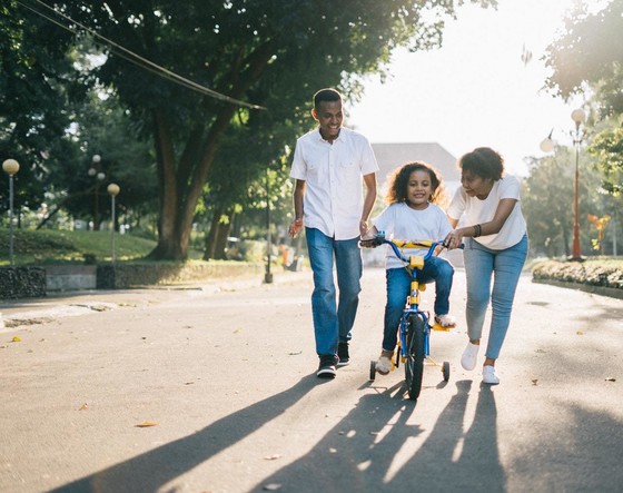 A family of three teaching child to ride a bike