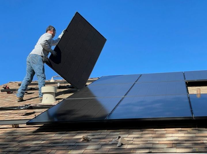 roofer laying solar panels on a sunny day