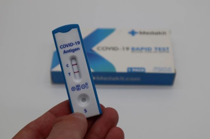 COVID-19 rapid flow test showing positive held between fingers