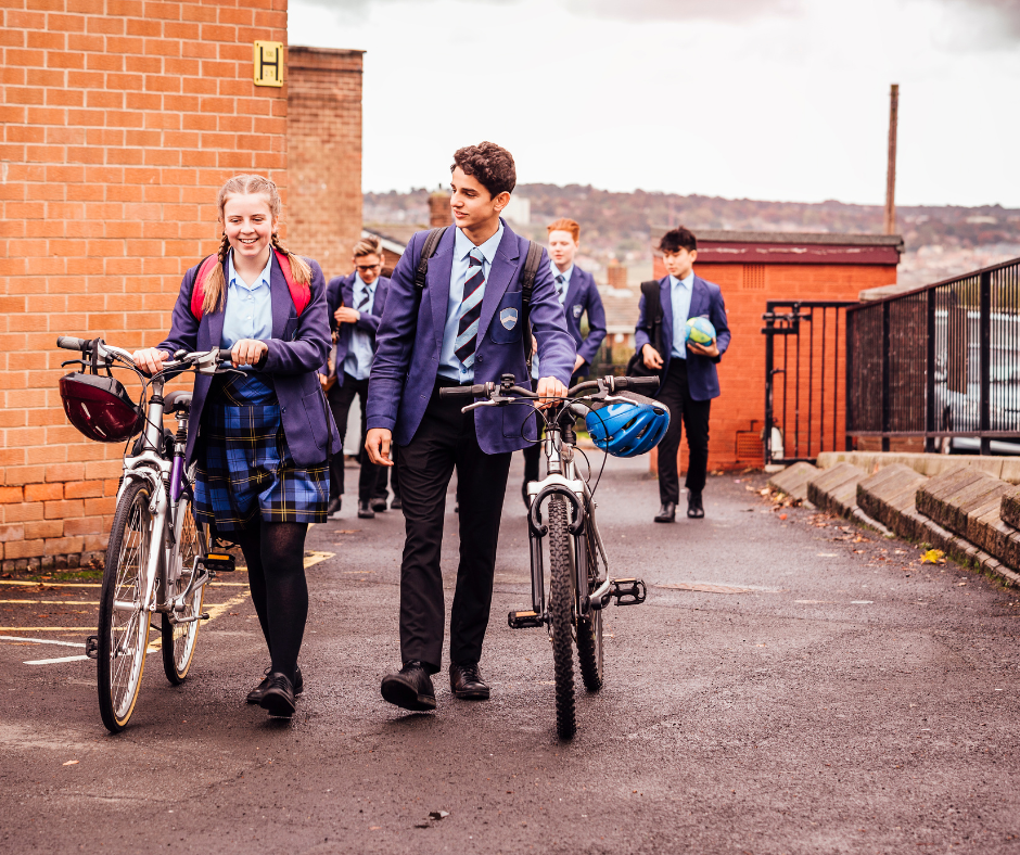 Two school pupils wheeling their bikes