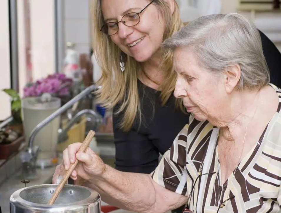 Woman with older lady helping her to cook