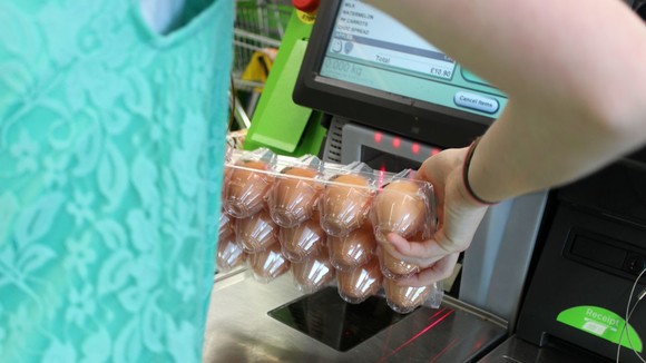 a person scanning some eggs through the self-service checkout at a supermarket
