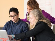 three people working around a laptop