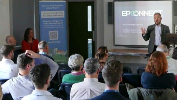 Photo shows a room of people with a speaker at the front talking to them - taken at the launch of the Decarbonise Devon programme