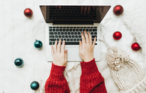 Hands typing surrounded by christmas decorations