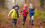 Children smiling running through woodland