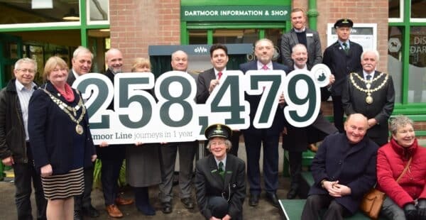 Dignitaries gathered on the platform at Okehampton to mark the one-year anniversary. They are holding up a  sign reading 258,479 (passenger journeys)