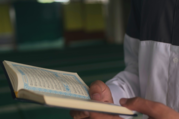Close up of a man holding a Quran in a prayer space