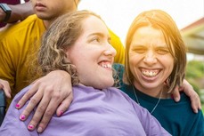 Young person being supported by worker smiling with hand over shoulder