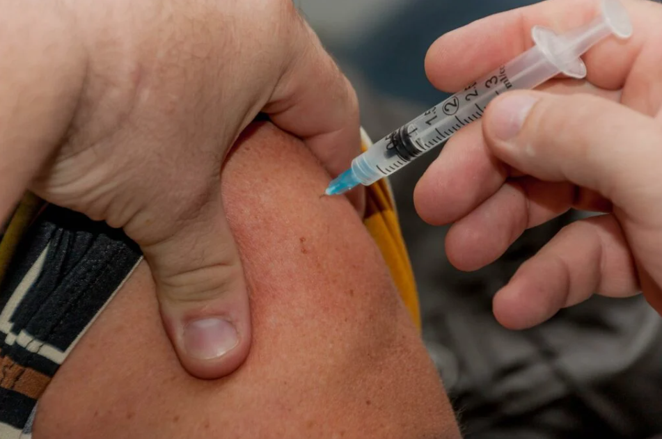 Person being injected with COVID-19 vaccine, close up of arm and needle