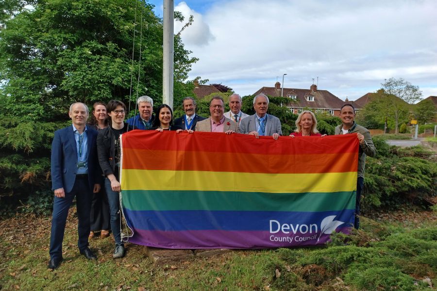 A group of people from Devon County Council gathered with the rainbow flag before it was raised above County Hall