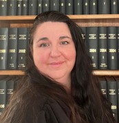 Maria Price standing in front of a bookcase filled with law books