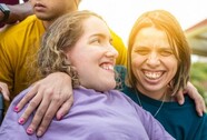 Image of two young women smiling one with her are around the other