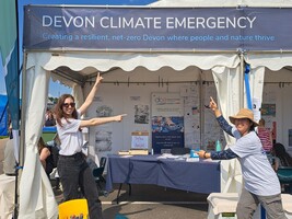 Two women point at a Devon Climate Emergency banner