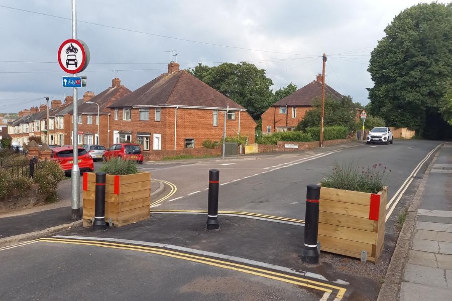 A bollard and a planter placed across a residential road to prevent vehicular access
