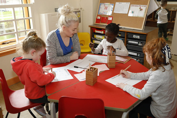 nursery worker interacting happily with three young children