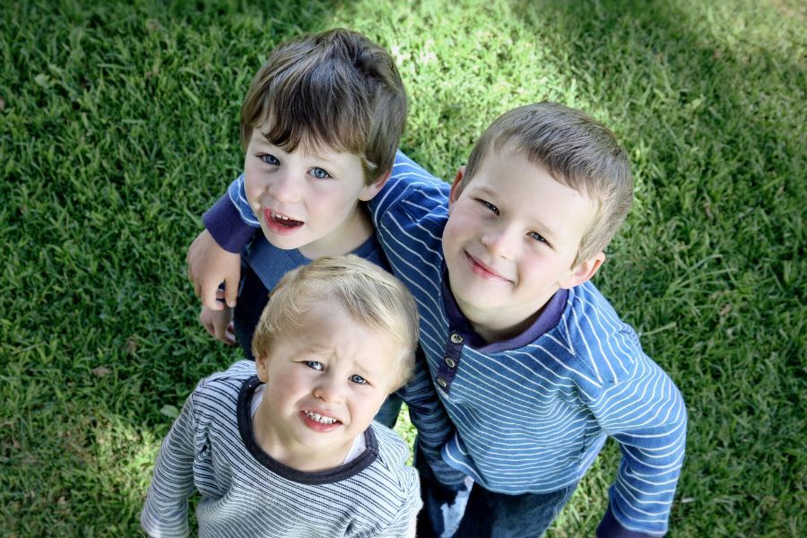 three young children stood, looking up and smiling at the camera
