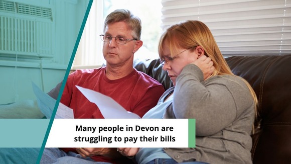 Couple looking worried at bills. Text reads: Many people in Devon are struggling to pay their bills