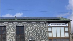 Totnes Civic Hall - a grey stone building with small windows just under the eaves and solar PV on the roof