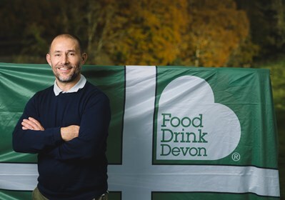 Man stood in front of Food Drink Devon flag