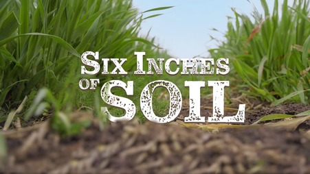 Six Inches of Soil logo on background of soil and grass
