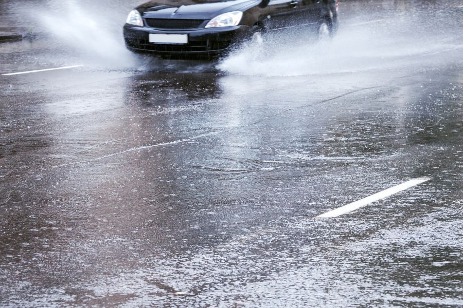 Car driving in wet weather with spray from the car tyres