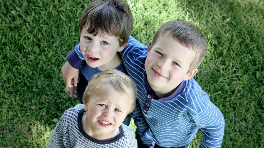three primary school age white boys smiling up at the camera