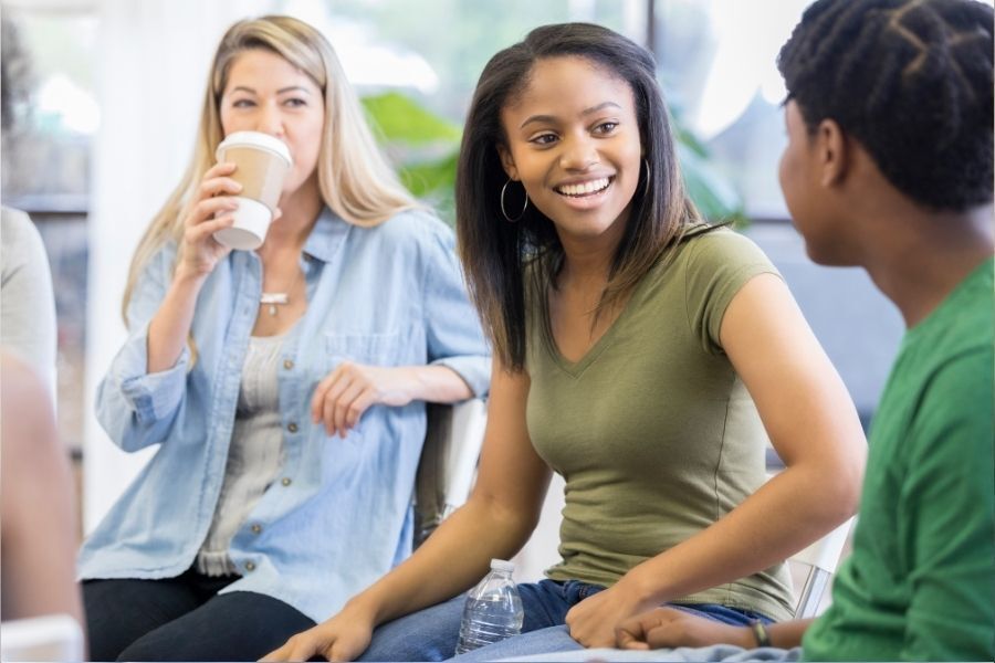 Girl in her late teens talking to adults in a group