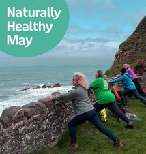A group of ladies being active in nature and performing lunges against a stone wall overlooking the the ocean, waves and rocks below.