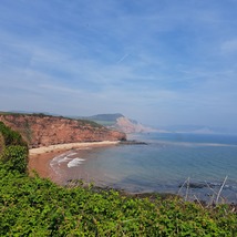 View of the cliffs of Budleigh Salterton with the grassy hills, beaming sun and ocean below