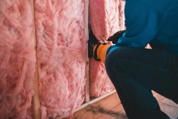 person kneeling installing wall insulation