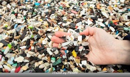 a hand reaches into a pile of marine plastic fragments