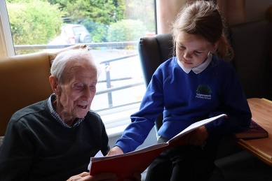 child reading to man in care home setting