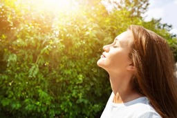 A woman faces the sun with her eyes closed