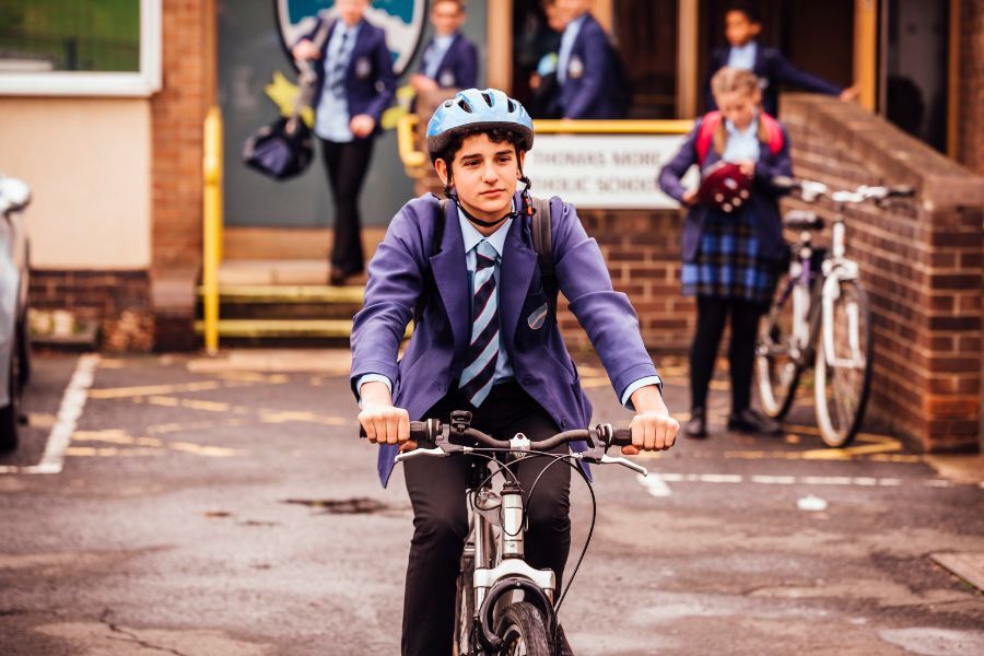 boy riding bike out of school