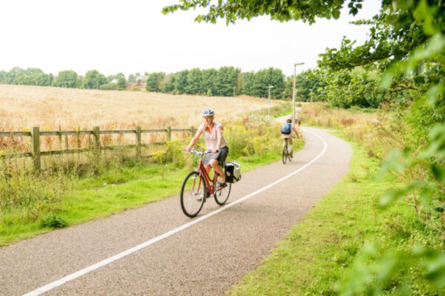 A person riding their bike on a cycle path through a green space