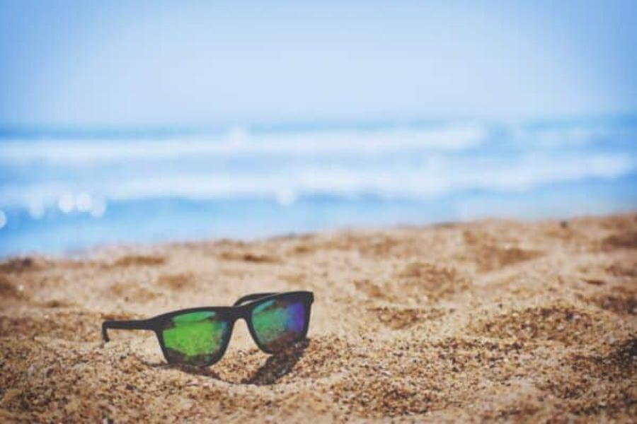 A pair of sunglasses on a beach on a sunny day